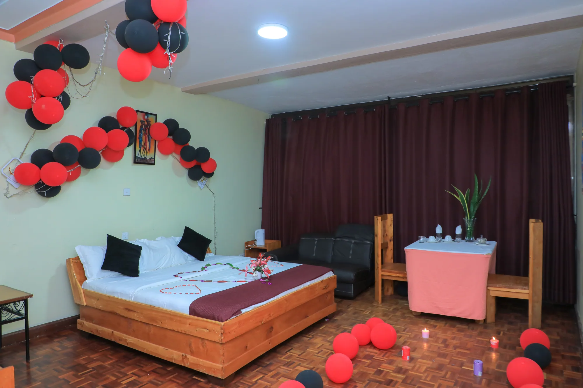 Deluxe Triple Room with white bedding beneath a red and black balloon arch and petals on the tiled floor