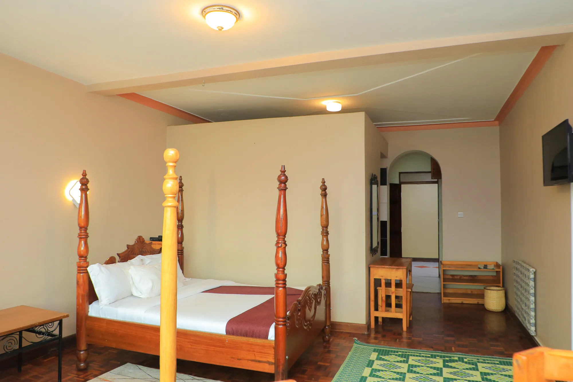 Single Room with a light-wood four-poster bed, patterned green floor, arched doorway and writing desk